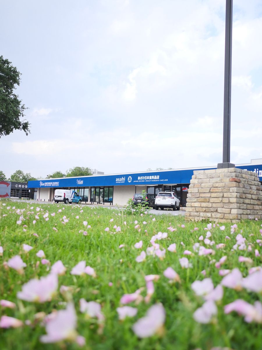 Asahi Japanese Market storefront in Houston behind a field of pink primrose