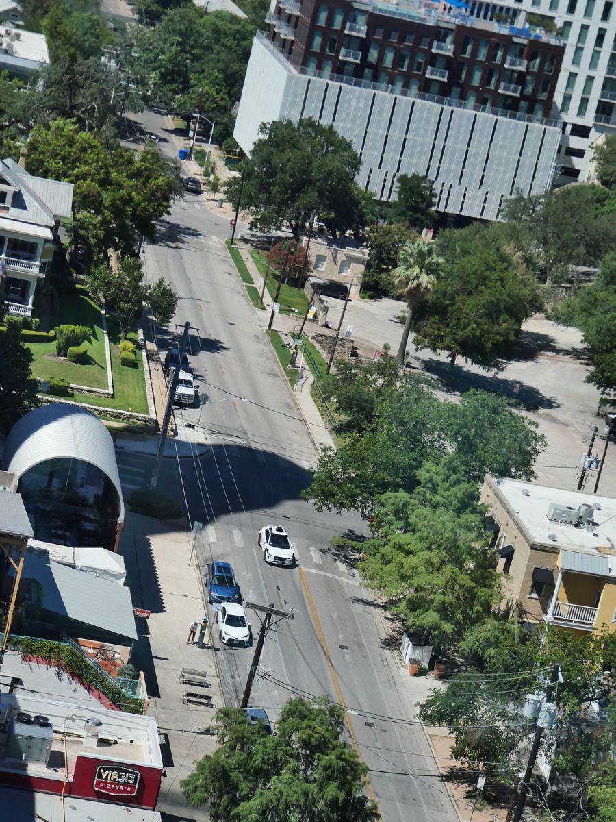 Texas street corner seen from high above, cars and rooftops in bright sun