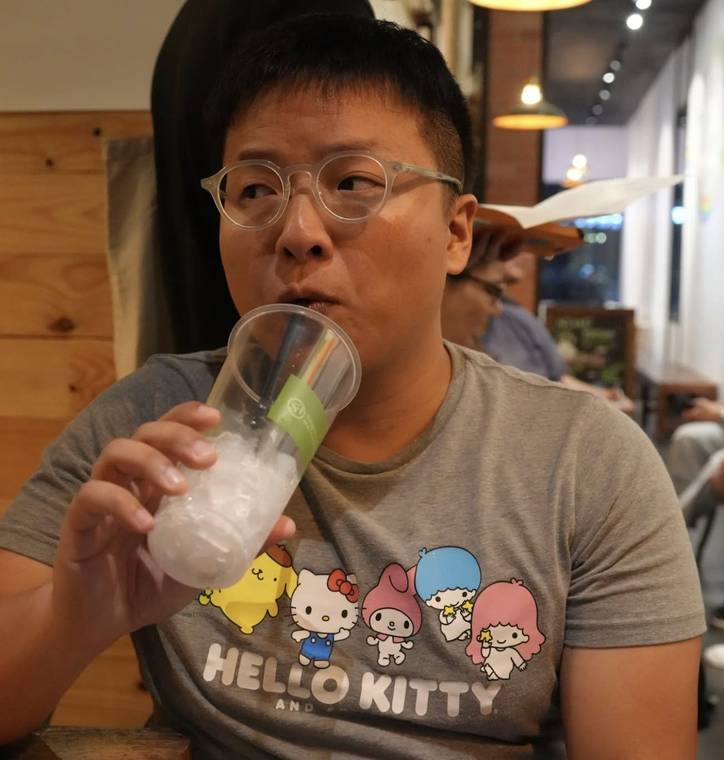 Jacky drinking boba at a cafe, wearing a Hello Kitty and friends t-shirt