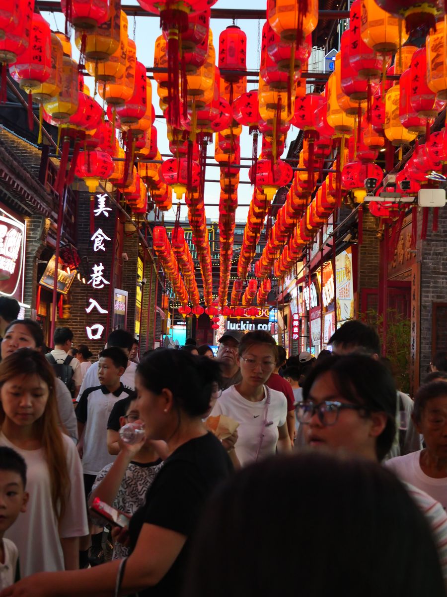 Crowded food street under rows of red and orange paper lanterns