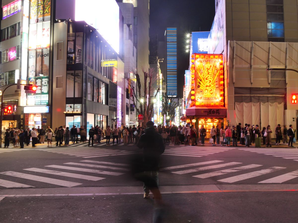 Crowd waiting at a neon-lit Shinjuku crossing at night
