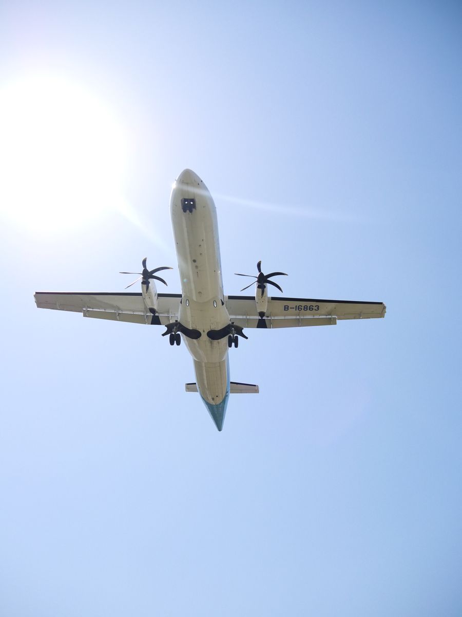 Twin-engine turboprop airliner passing directly overhead against the sun